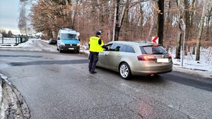 Policjant przeprowadza badanie na zawartość alkoholu w wydychanym powietrzu kierującego.