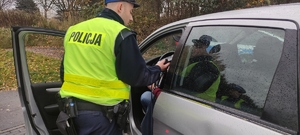 Policjant sprawdza stan trzeźwości kierującego.