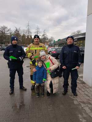 Policjanci, strażak Ochotniczej Straży Pożarnej i dziecko, które otrzymało odblask.