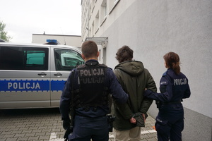 Na zdjęciu policjanci doprowadzają podpalacza.