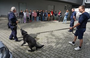 Na zdjęciu policjanci, przewodnik psa wraz ze swoim pupilem opowiadają dzieciom o służbie w Policji.