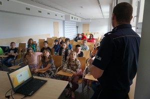 Na zdjęciu policjant, który rozmawia z dziećmi o bezpieczeństwie.