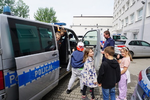 Na zdjęciu dzieci oglądają policyjny radiowóz.