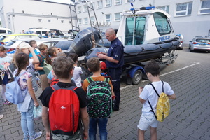 Na zdjęciu dzieci oglądają policyjny radiowóz.