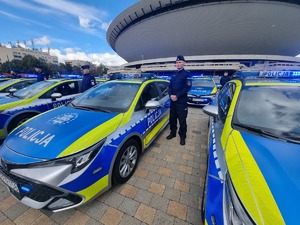 Na zdjęciu policjant oraz nowe oznakowane radiowozy.