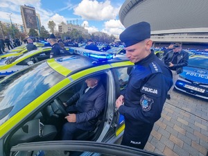 Na zdjęciu policjant prezentuje radiowóz Burmistrzowi.