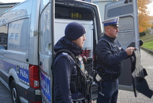 Na zdjęciu policjanci prezentują dzieciom kamizelkę.