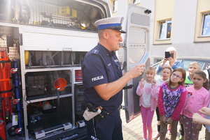 Na zdjęciu policjant pokazuje dzieciom radiowóz.