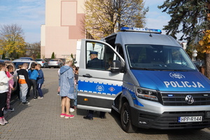 Na zdjęciu policjant prezentuje dzieciom oznakowany radiowóz.