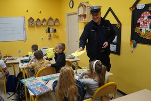 Na zdjęciu policjant z rybnickiej drogówki rozdaje dzieciom odblaski.