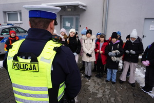 Policjant ruchu drogowego prowadzi pogadankę na temat bezpieczeństwa podczas zimowego wypoczynku.