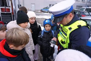 Na zdjęciu policjant ruchu drogowego pokazuje dzieciom policyjny sprzęt.