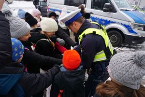 Na zdjęciu policjant rozdaje dzieciom odblaski.