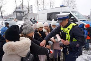 Na zdjęciu policjant rozdaje dzieciom odblaski.