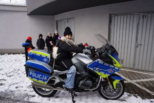 Na zdjęciu dzieci podczas wizyty w rybnickiej komendzie oglądają policyjny motocykl.