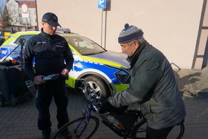 Na zdjęciu policjant wręcza rowerzyście odblask.