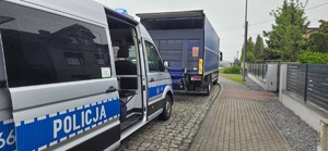 Zdjęcie przedstawia pojazd oznakowany policji wydziału ruchu drogowego oraz zatrzymaną cieżarówkę do kontroli