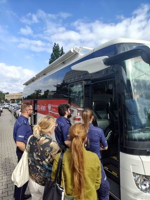 Na zdjęciu policjanci oraz mieszkańcy czekający przed autokarem.
