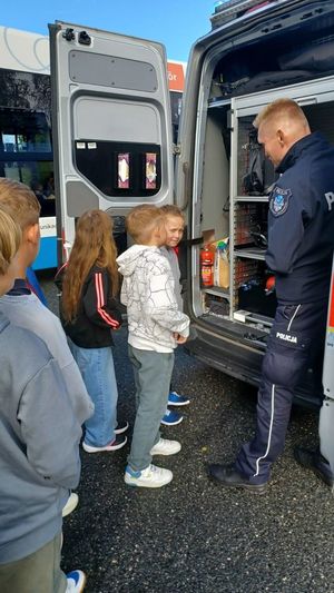 Na zdjęciu policjant prezentuje dzieciom policyjny radiowóz.