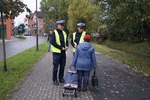 Na zdjęciu policjanci wręczają kobiecie odblask.