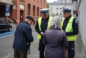 Na zdjęciu policjanci wręczają mieszkańcom elementy odblaskowe.
