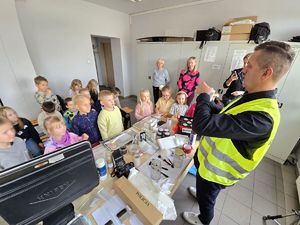 Na zdjęciu technik kryminalistyki prezentuje, jak zabezpieczyć ślady na miejscu zdarzenia.