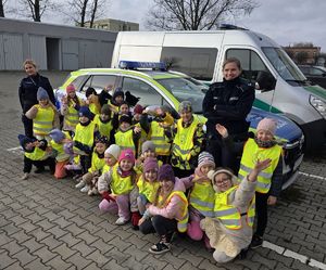 Na zdjęciu przedszkolaki. W tle radiowóz.