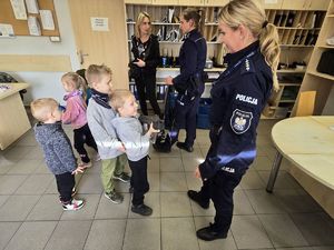 Na zdjęciu policjantka pokazuje dzieciom broń.