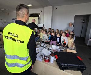Na zdjęciu technik kryminalistyki opowiada przedszkolakom o swojej pracy.