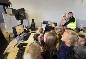 Na zdjęciu technik kryminalistyki prezentuje dzieciom, jak zabezpieczyć ślady.