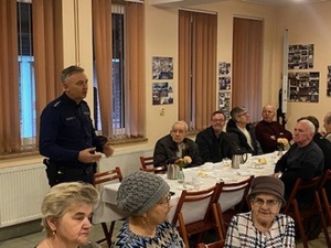 Na zdjęciu dzielnicowy rozmawia z seniorami o bezpieczeństwie.