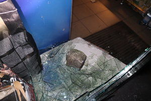 Na zdjęciu wybita szyba i kamień.