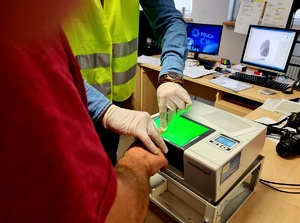 Policjant prowadzi daktyloskopię.