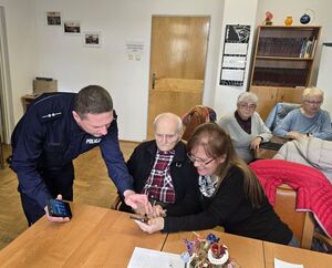 Na zdjęciu policjantka uczy seniorów obsługi telefonów komórkowych.