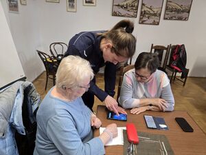 Na zdjęciu policjantka uczy seniorki obsługi telefonu komórkowego.