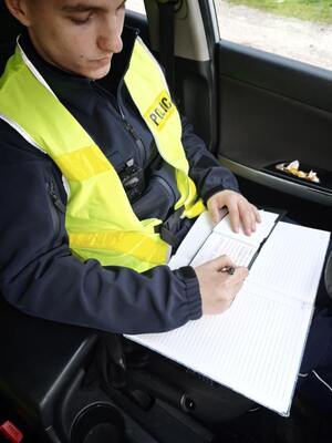Na zdjęciu policjant wypisujący mandat karny.